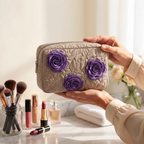 Trousse de maquillage matelassée Rose Enchantée tenue en main près de la coiffeuse