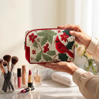 Trousse de maquillage matelassée Cardinal et Houx tenue en main près de la coiffeuse