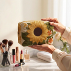 Trousse de maquillage matelassée Fleur Éclatante tenue en main près de la coiffeuse