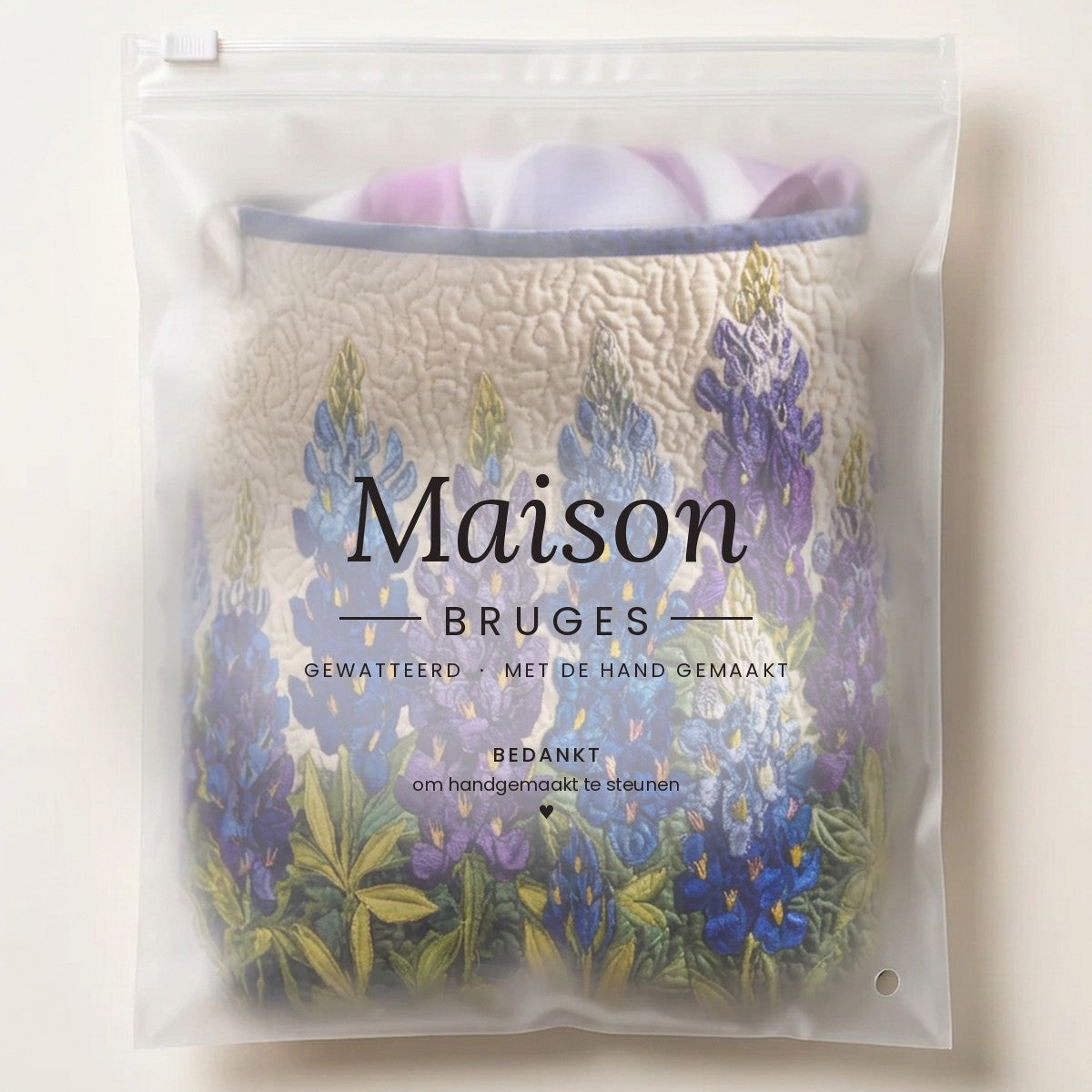 Panier à linge matelassé Rêve de lupins bleus, plié à plat dans l’emballage Maison Bruges
